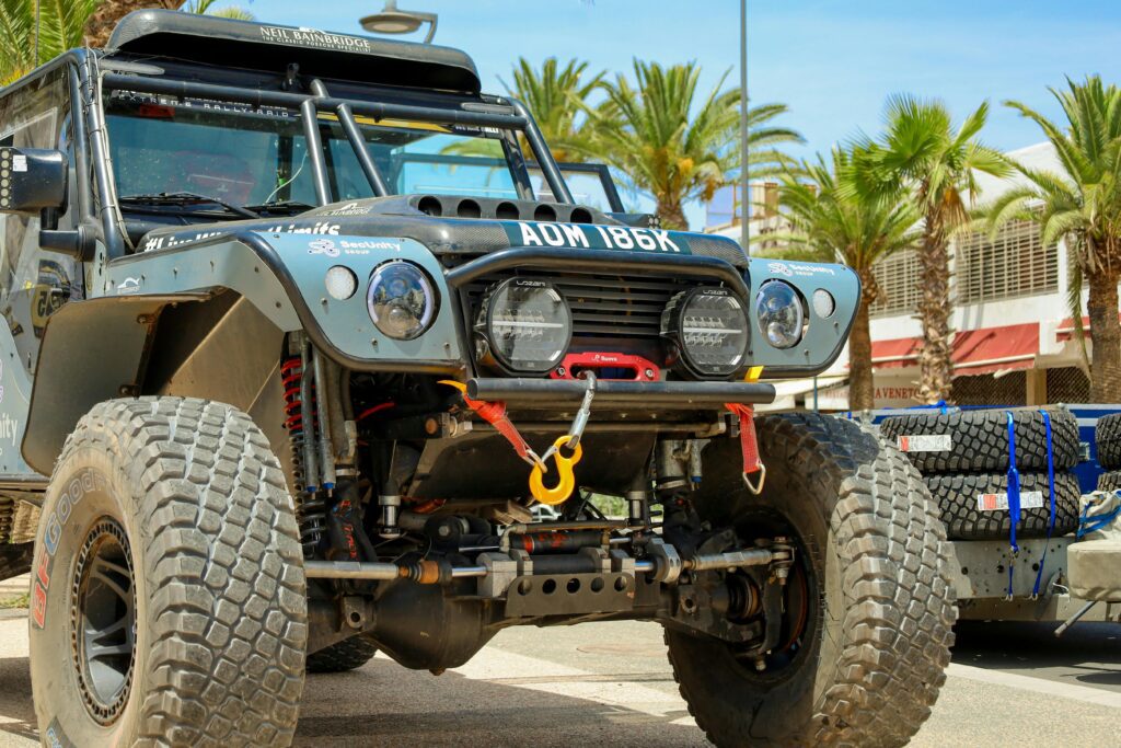 Close-up of a rugged off-road vehicle with large tires and winch in a sunny outdoor setting.