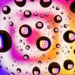 Vibrant water droplets on a colorful background reflecting Instagram logos, showcasing abstract digital creativity.